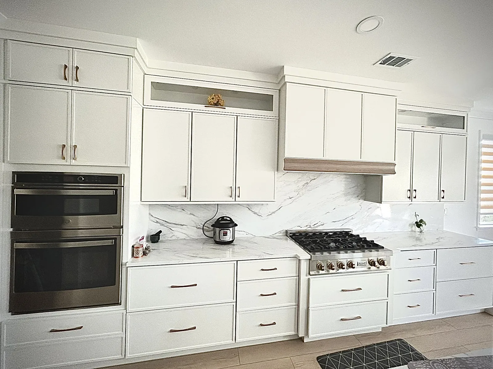 Completed kitchen remodel by HQ Construction & Remodeling with white cabinetry, countertops, backsplash and built-in appliances