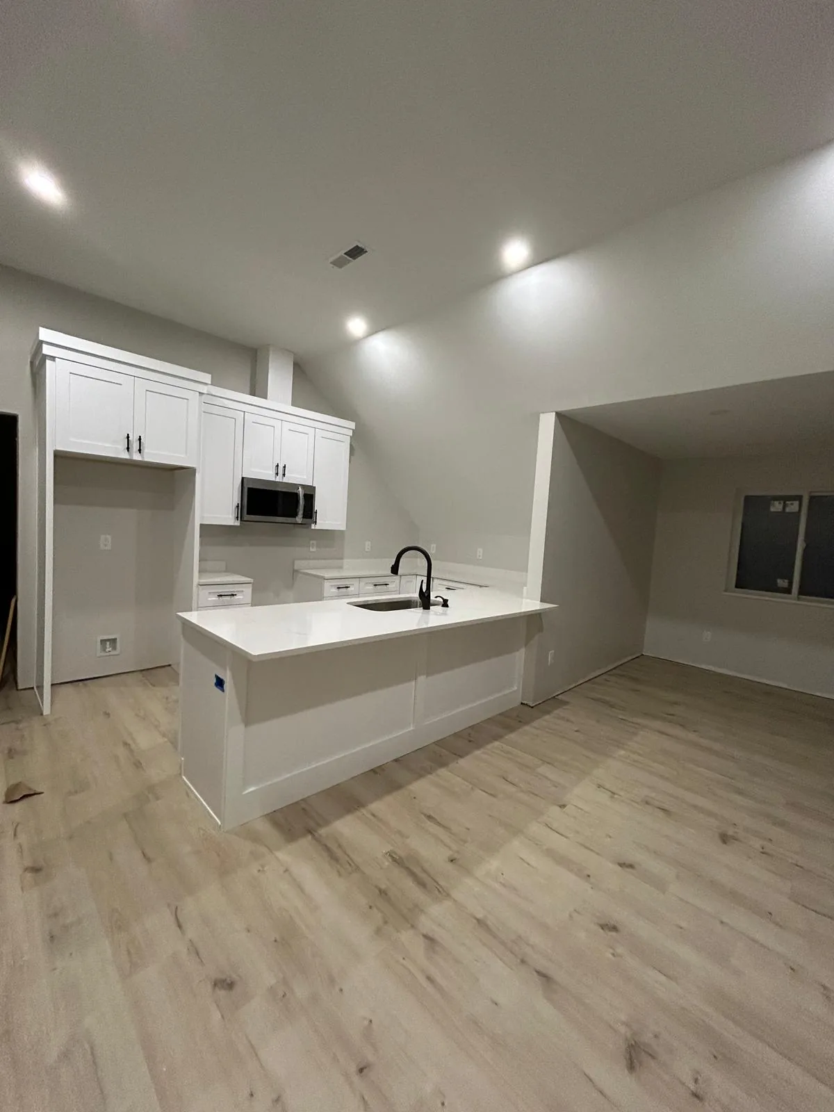 Completed kitchen remodel by HQ Construction & Remodeling with island, flooring and recessed lighting